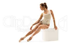 Photo of ballet dancer gracefully sitting on cube