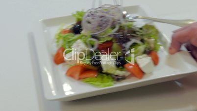 Waiter Puts A Plate With Greek Salad  On A Table