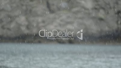 Rain On Calm Sea With Rocks In Background