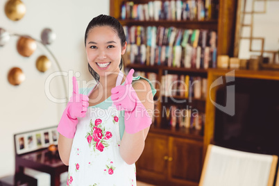 Composite image of woman wearing rubber gloves giving thumbs up