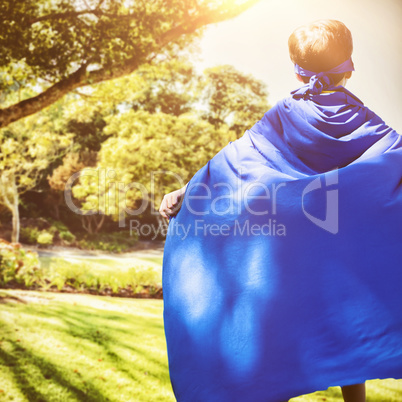 Composite image of boy in blue cape standing