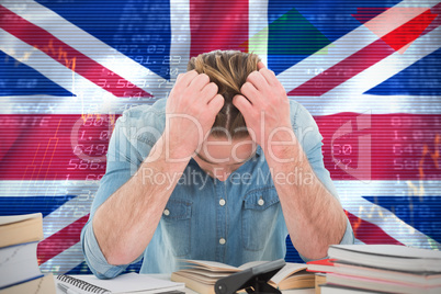 Composite image of frustrated man with hand in hair while sitting at desk