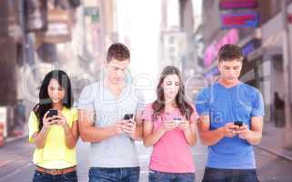 Composite image of four people standing beside each other and texting on their phones