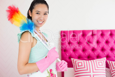 Composite image of smiling woman with duster