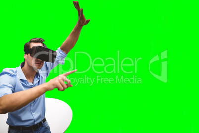 Composite image of man pointing while wearing virtual reality simulator