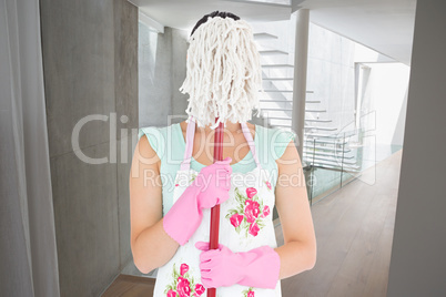 Composite image of woman hiding her face with a mop