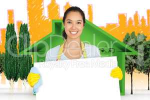 Composite image of woman in apron and rubber gloves holding white surface