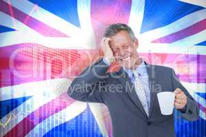 Composite image of businessman suffering from headache while holding coffee cup