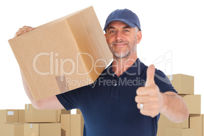 Composite image of happy delivery man holding cardboard box showing thumbs up