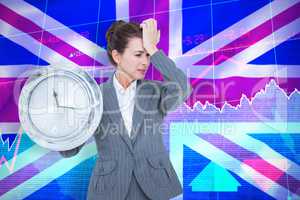 Composite image of upset businesswoman holding wall clock