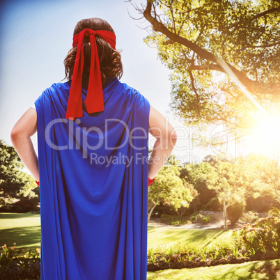 Composite image of boy in blue cape standing