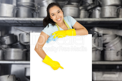 Composite image of happy cleaning lady pointing to white surface
