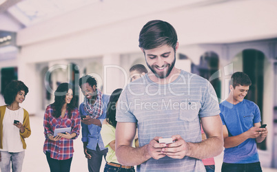 Composite image of smiling young man using phone