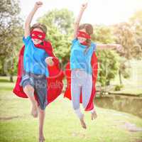 Composite image of playful siblings disguise as superhero