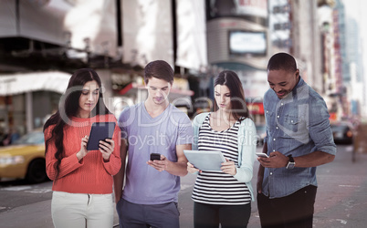 Composite image of young creative team looking at phones and tablets