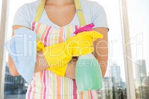 Composite image of woman holding window cleaner and rag