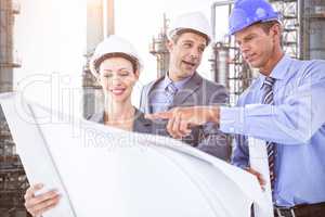 Composite image of businessmen and a woman with hard hats and holding blueprint