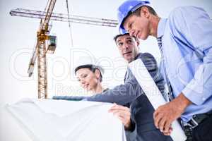 Composite image of businessman explaining a blueprint to his colleagues