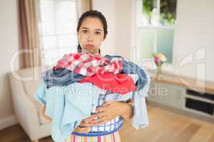 Composite image of tired woman holding full laundry basket