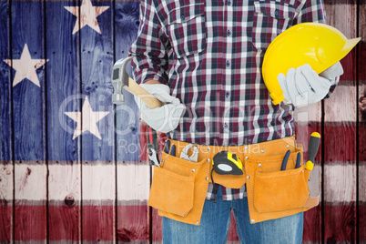 Composite image of handyman holding hard hat and hammer
