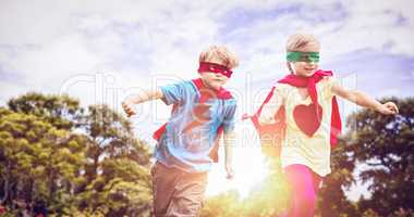 Composite image of playful siblings playing together while disguise as superhero