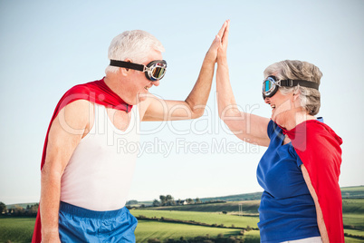 Composite image of senior couple wearing superman costume