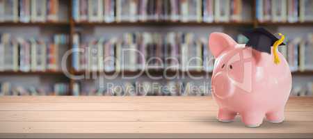 Composite image of piggy bank with graduation hat
