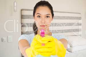 Composite image of brunette woman pointing spray bottle