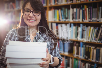 Portrait of female students holding a pile of books in library