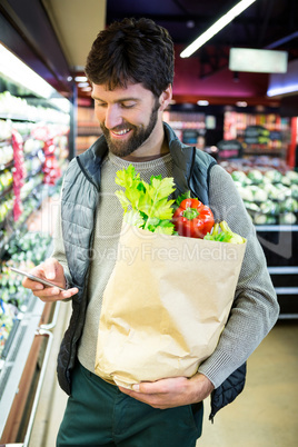Man using mobile phone while holding grocery bag
