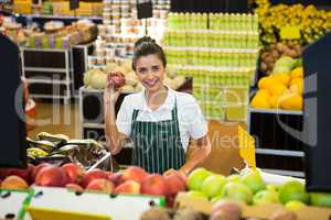 Female staff holding fruit in organic section of supermarket