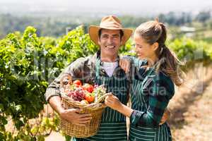 Happy farmer couple holding a basket of vegetables