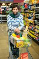 Portrait of smiling man with trolley in grocery section