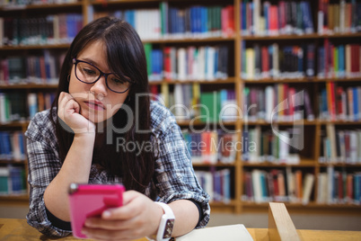 Thoughtful female student using a mobile phone