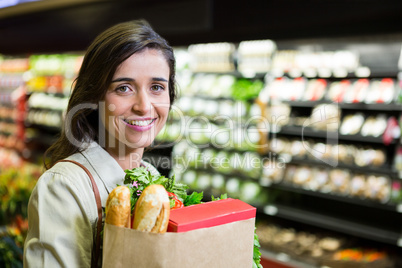 Portrait of smiling woman holding a grocery bag in organic section