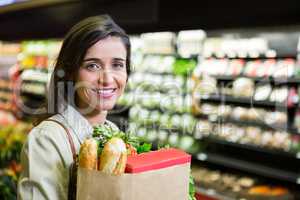 Portrait of smiling woman holding a grocery bag in organic section