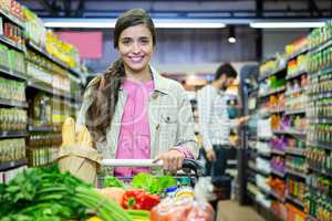 Portrait of woman with vegetables in shopping trolley