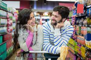 Couple leaning on trolley at supermarket