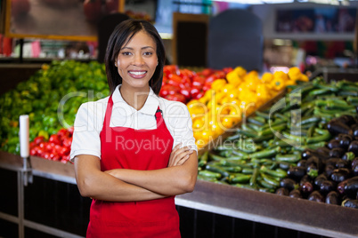 Smiling female staff standing with arms crossed in organic section