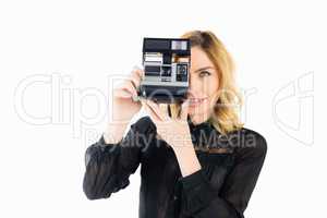 Smiling woman clicking photo from camera against white background