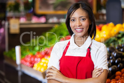 Smiling female staff standing with arms crossed in organic section