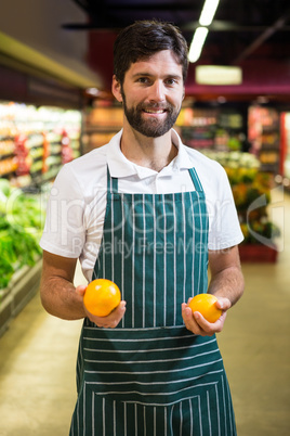 Smiling male staff holding fruit in organic section of supermarket