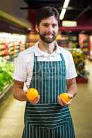 Smiling male staff holding fruit in organic section of supermarket