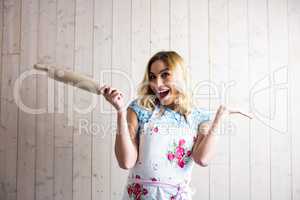 Woman in apron holding a rolling pin against texture background