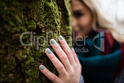 Woman hiding behind tree trunk