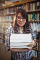 Portrait of female students holding a pile of books in library