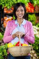 Smiling woman holding fruits and vegetables in basket