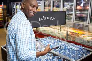 Man looking at bottle of water in supermarket