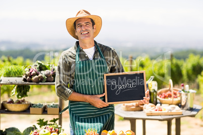 Portrait of smiling farmer holding an organic sign