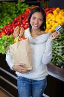 Woman holding credit card and grocery bag